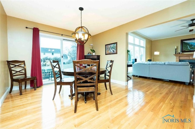 dining area with hardwood / wood-style floors, ceiling fan with notable chandelier, ornamental molding, and a healthy amount of sunlight