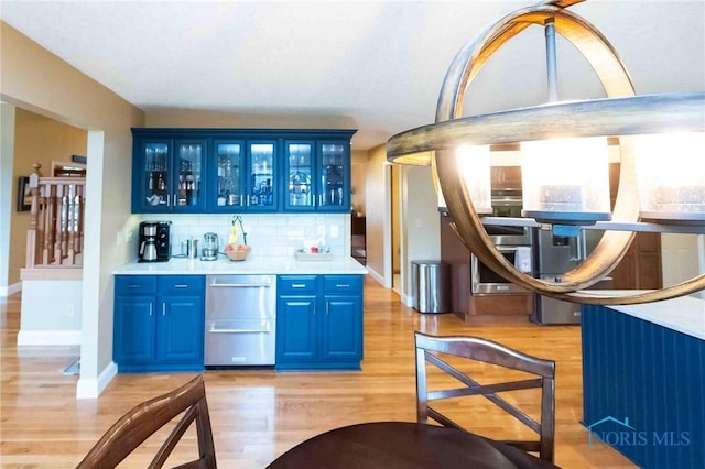 bar with backsplash, light hardwood / wood-style floors, and blue cabinets