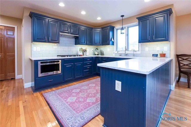 kitchen featuring blue cabinetry, appliances with stainless steel finishes, and decorative light fixtures