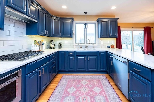 kitchen featuring appliances with stainless steel finishes, sink, pendant lighting, and blue cabinetry