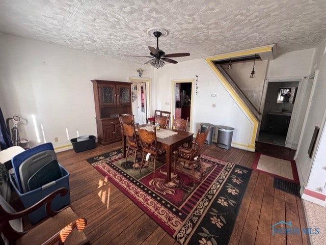 dining space with ceiling fan, a textured ceiling, and dark hardwood / wood-style flooring