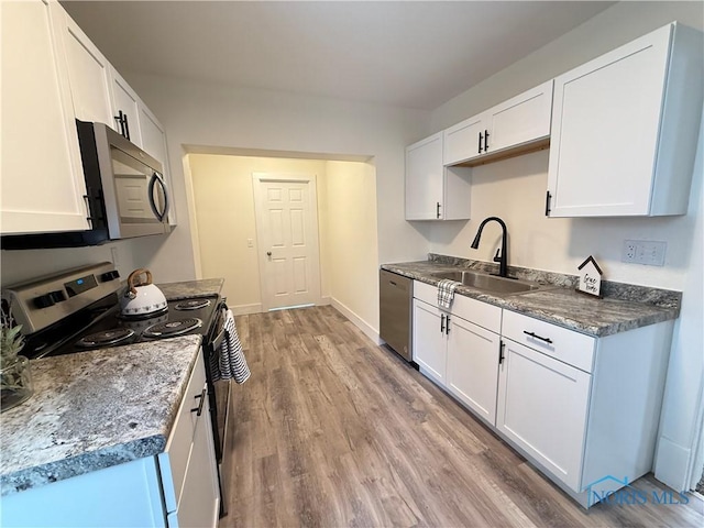 kitchen featuring white cabinetry, sink, light hardwood / wood-style floors, and appliances with stainless steel finishes