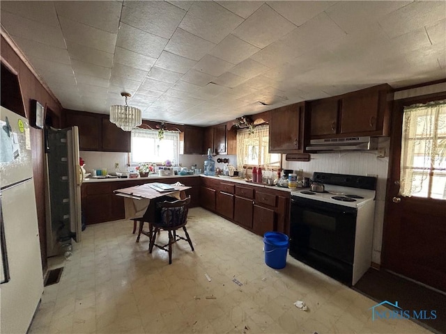 kitchen with white fridge, electric range oven, and pendant lighting