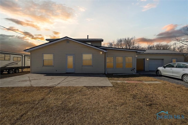 rear view of property with a garage, a patio area, and a yard