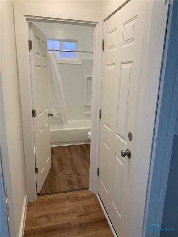 bathroom featuring shower / tub combo with curtain, hardwood / wood-style flooring, and toilet