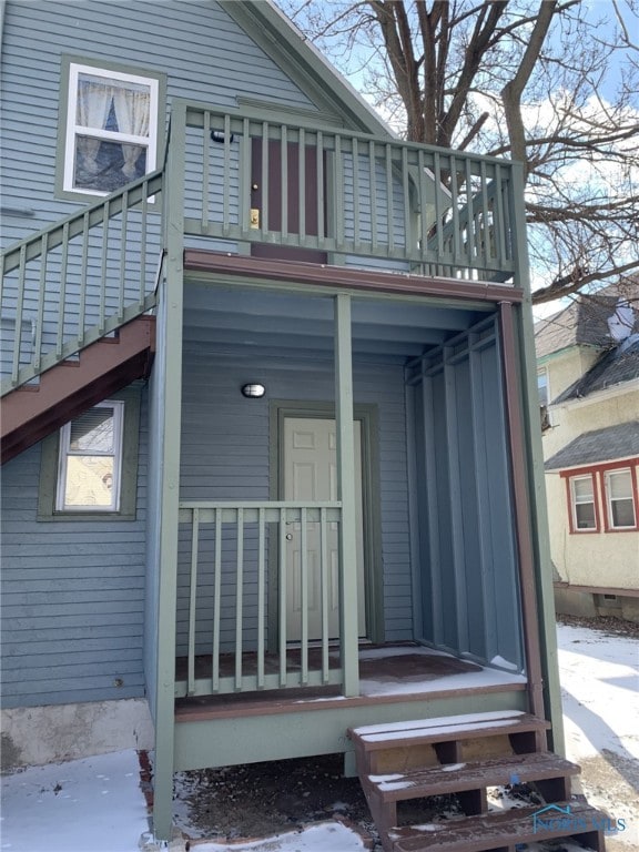 snow covered rear of property with a porch