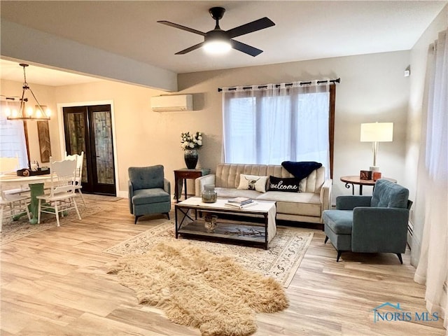 living room featuring ceiling fan with notable chandelier, a wealth of natural light, light hardwood / wood-style floors, and an AC wall unit