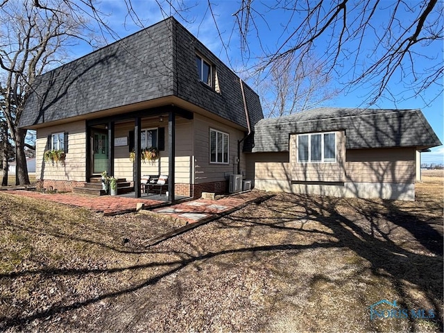 back of house featuring a patio area, a shingled roof, mansard roof, and central AC