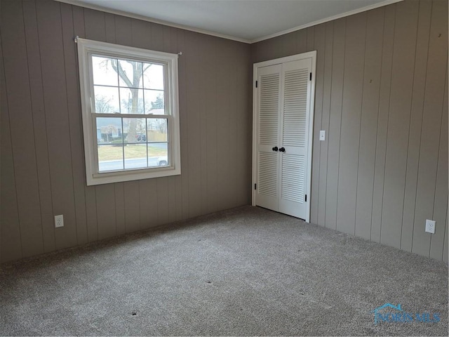 unfurnished bedroom featuring crown molding, a closet, and carpet flooring