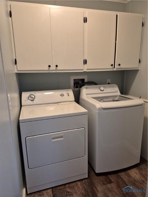 laundry room with cabinets, washing machine and clothes dryer, and dark wood-type flooring