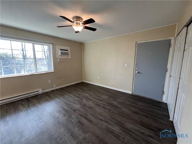 spare room featuring a baseboard radiator, dark wood-type flooring, a wall mounted AC, and a textured ceiling