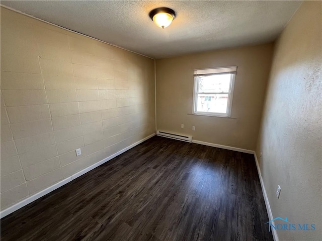 empty room with a baseboard radiator, dark hardwood / wood-style floors, and a textured ceiling