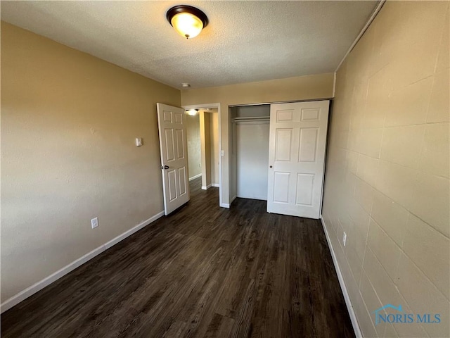 unfurnished bedroom featuring dark wood-type flooring, a closet, and a textured ceiling