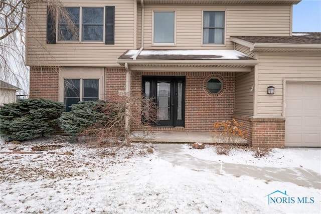 snow covered property entrance with a garage