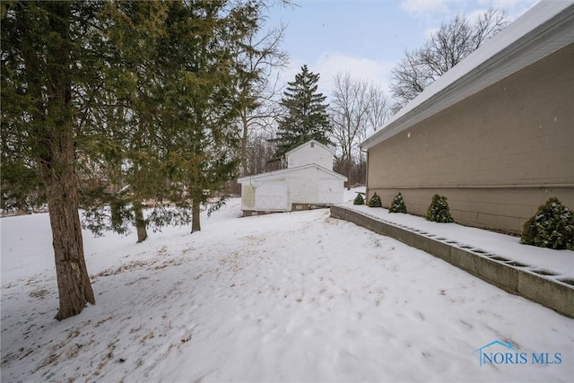 snowy yard featuring a storage unit