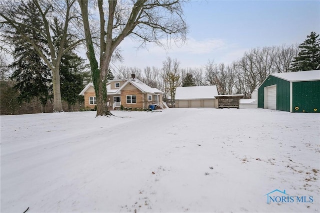 yard layered in snow featuring an outbuilding and a garage