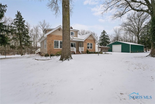 snow covered rear of property featuring an outbuilding and a garage