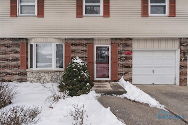 snow covered property entrance with a garage