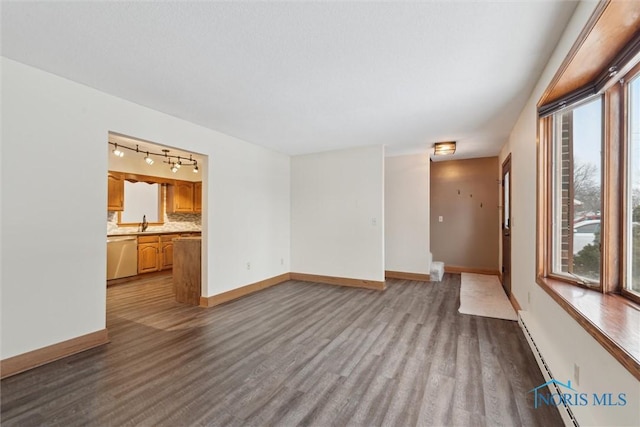 unfurnished living room with light hardwood / wood-style floors, a wealth of natural light, sink, and a baseboard heating unit