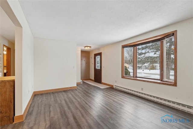 empty room featuring a baseboard radiator, hardwood / wood-style flooring, and a textured ceiling