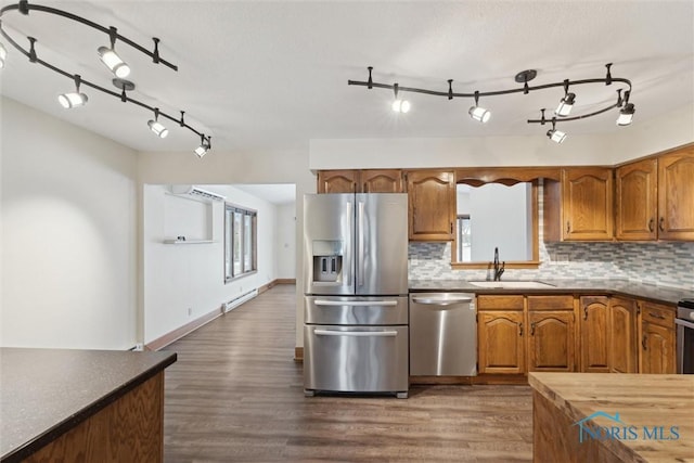 kitchen with tasteful backsplash, appliances with stainless steel finishes, dark wood-style floors, and brown cabinets