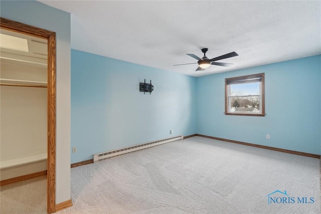 unfurnished bedroom with baseboard heating, ceiling fan, and carpet