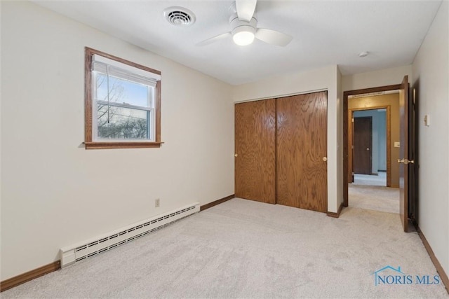 unfurnished bedroom with a closet, light colored carpet, visible vents, a baseboard heating unit, and baseboards