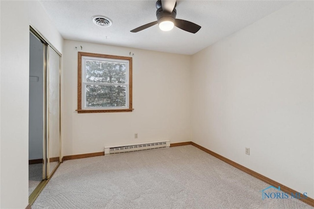 unfurnished bedroom featuring visible vents, baseboards, a closet, baseboard heating, and light carpet