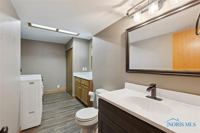 bathroom with washer / clothes dryer, hardwood / wood-style flooring, toilet, and vanity