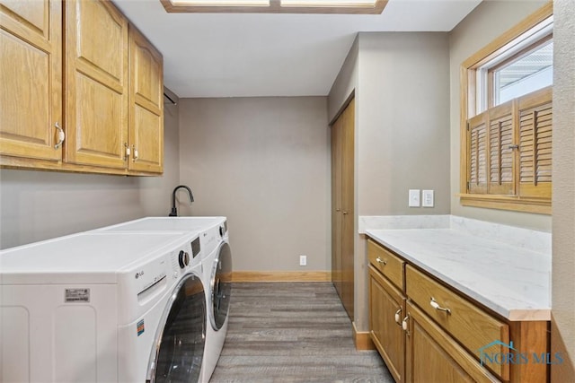 laundry area with washer and dryer, cabinets, and light wood-type flooring