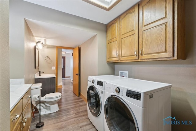 washroom featuring light hardwood / wood-style flooring, washer and clothes dryer, and sink