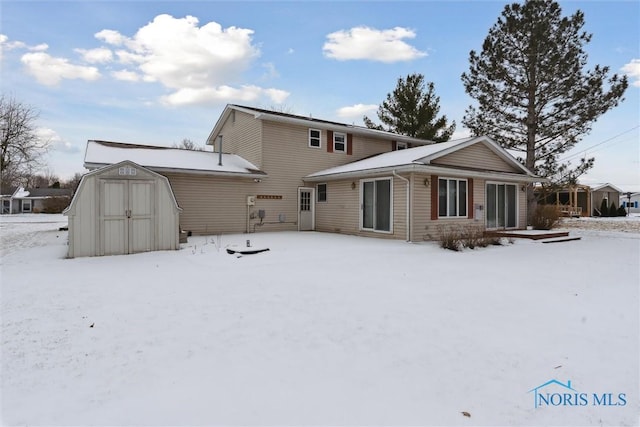 snow covered back of property featuring a storage unit