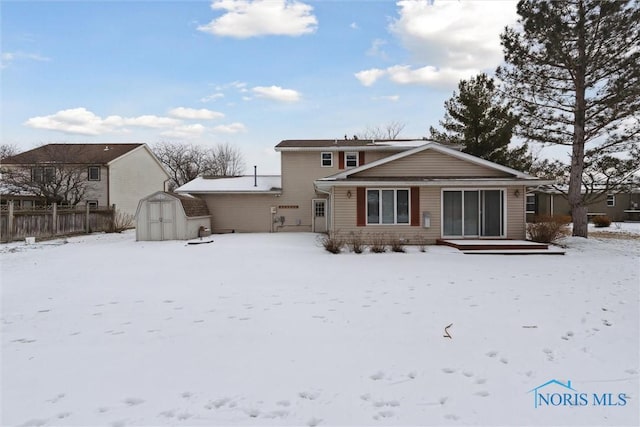 snow covered property featuring a storage shed, an outbuilding, and fence