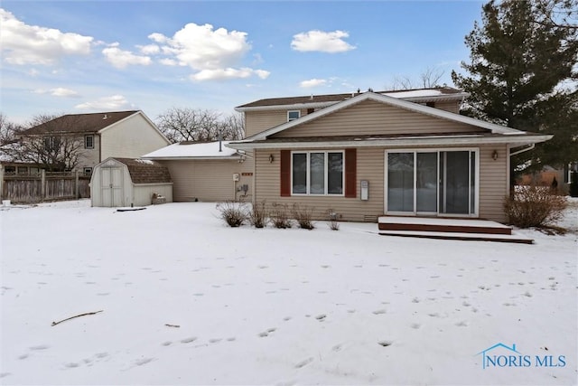 snow covered house featuring a storage shed