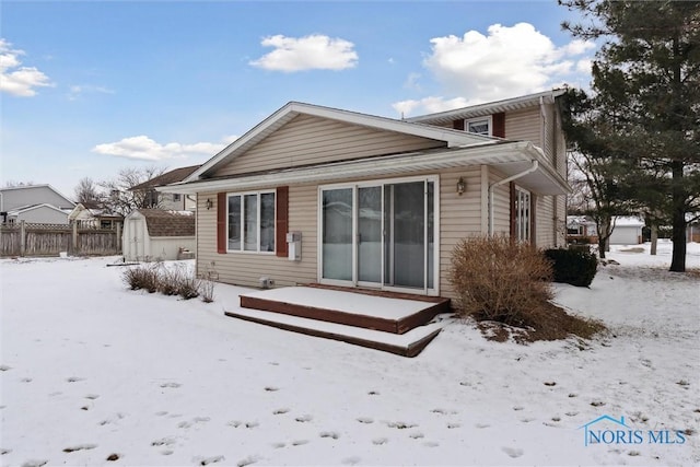 snow covered rear of property with a storage shed