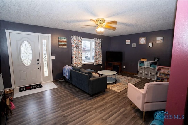 living room with ceiling fan, dark wood-type flooring, and a textured ceiling