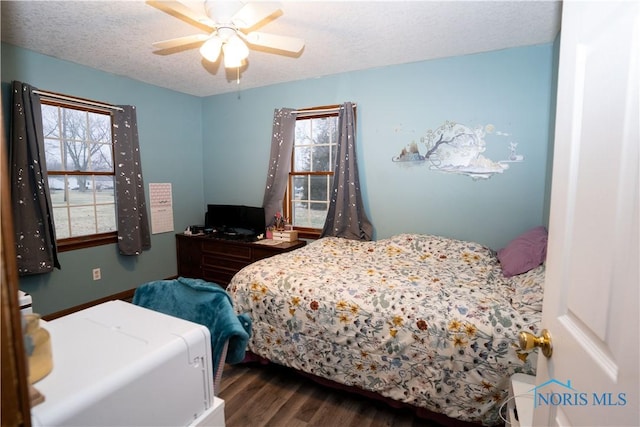 bedroom featuring ceiling fan, dark hardwood / wood-style floors, multiple windows, and a textured ceiling