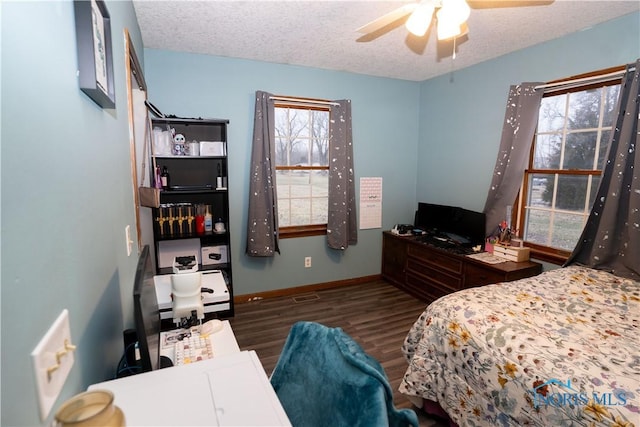 bedroom featuring dark hardwood / wood-style flooring, ceiling fan, and a textured ceiling