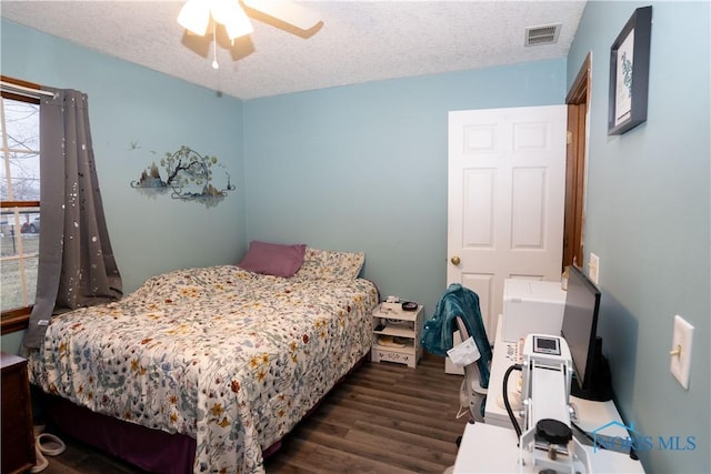 bedroom with ceiling fan, dark hardwood / wood-style floors, and a textured ceiling