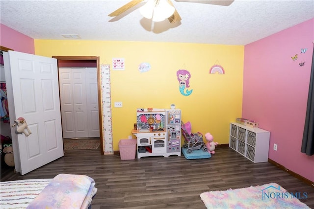 playroom with ceiling fan, dark hardwood / wood-style floors, and a textured ceiling