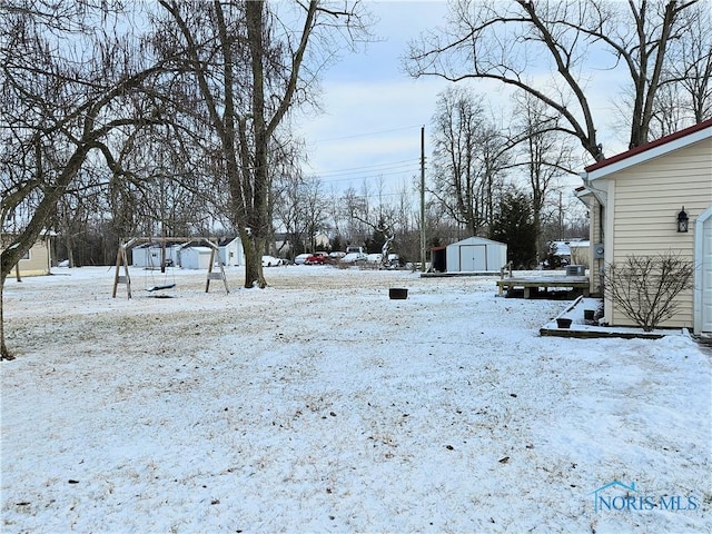 yard covered in snow featuring a storage unit