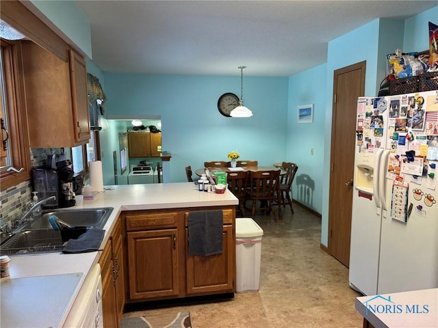 kitchen featuring sink, decorative backsplash, white fridge with ice dispenser, decorative light fixtures, and kitchen peninsula