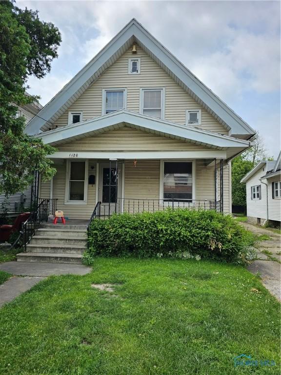 bungalow-style house with a front yard and covered porch