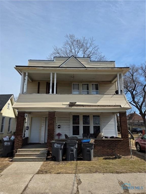 view of front of home featuring a porch, a balcony, and brick siding