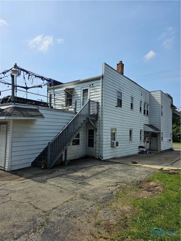 back of house with stairway, cooling unit, and a chimney