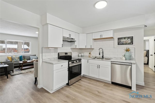 kitchen with light wood-type flooring, appliances with stainless steel finishes, sink, and white cabinets