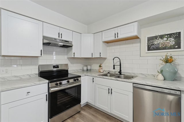 kitchen with sink, light wood-type flooring, appliances with stainless steel finishes, white cabinets, and backsplash