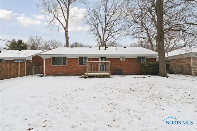 snow covered back of property featuring central AC unit