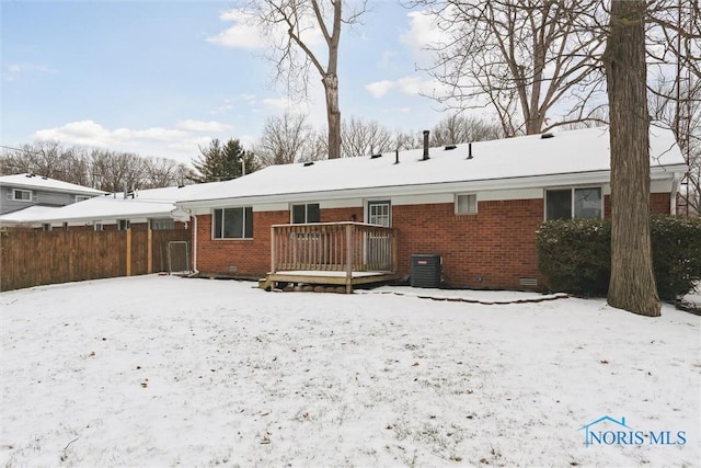 snow covered rear of property featuring a wooden deck and central AC