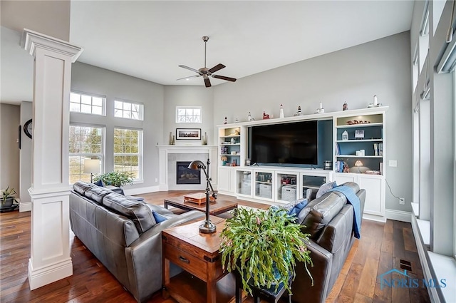 living room featuring decorative columns, ceiling fan, and dark hardwood / wood-style flooring